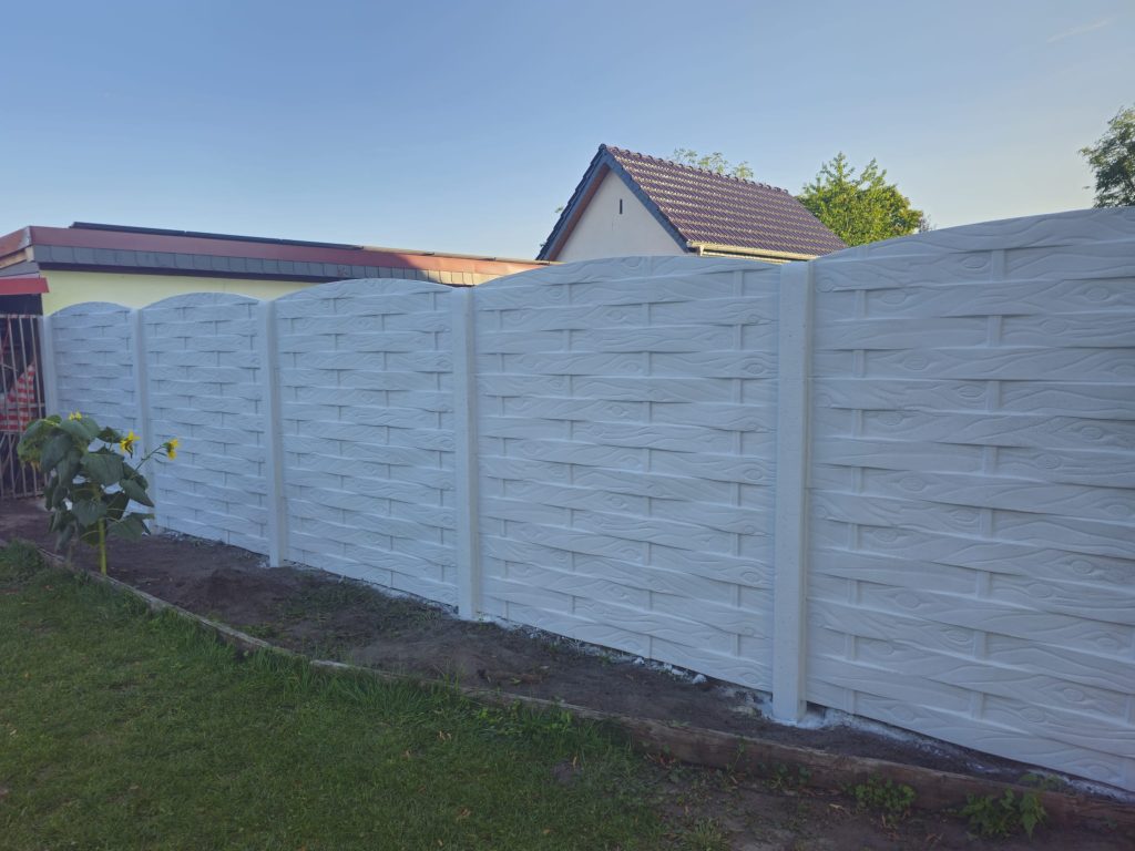 Heller Betonzaun in Holzstruktur an einem Garten